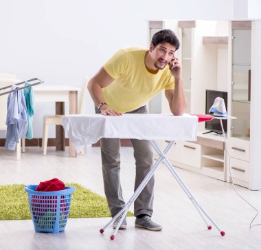Yakışıklı koca evde kıyafet ütülüyor.