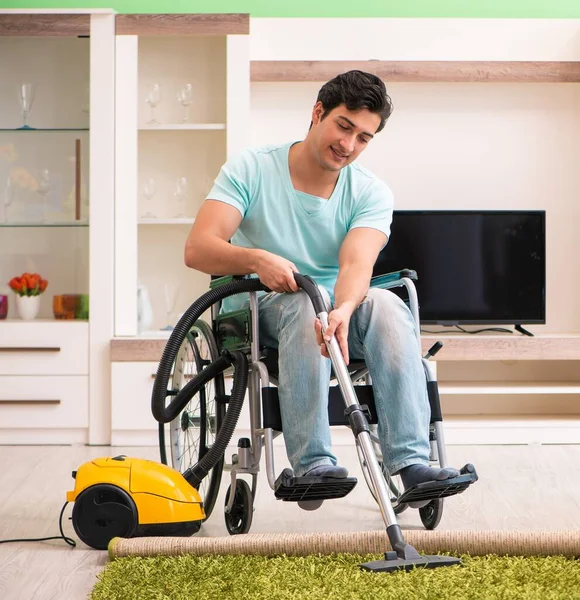 Hombre discapacitado en silla de ruedas casa de limpieza al vacío —  Fotos de Stock