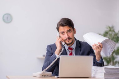 Genç erkek çalışan işyerinde oturuyor.