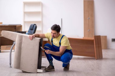 Genç erkek marangoz ofiste kol sandalyesini tamir ediyor.