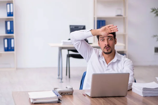 Joven empleado masculino y demasiado trabajo en la oficina — Foto de Stock