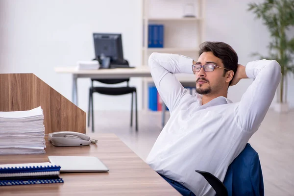 Jovem funcionário masculino e muito trabalho no escritório — Fotografia de Stock