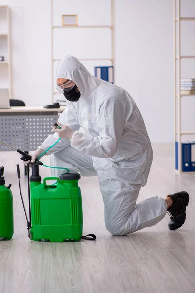Contratista masculino joven desinfectando oficina durante pandemia —  Fotos de Stock