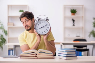 Genç erkek öğrenci zaman yönetimi konsepti sınavlarına hazırlanıyor.