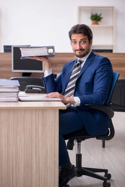 Jovem funcionário masculino e muito trabalho no escritório — Fotografia de Stock