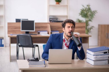 Genç alkol bağımlısı erkek çalışan ofiste çalışıyor.