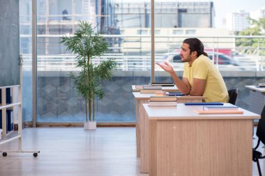 Sınıfta oturan genç erkek öğrenci.