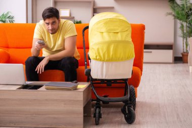 Genç adam evde yeni doğan çocuğa bakıyor.