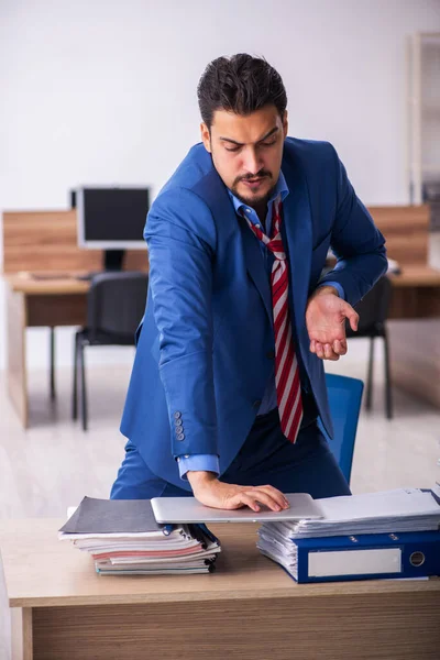 Giovane dipendente maschio infelice con un lavoro eccessivo sul posto di lavoro — Foto Stock