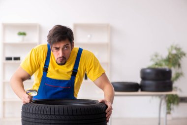 Atölyede lastiği olan genç bir erkek tamirci.