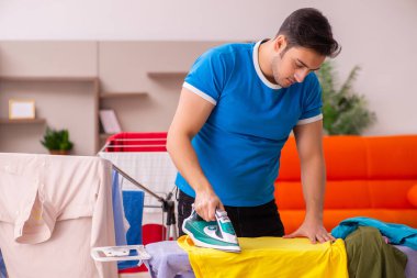 Genç adam evde ütü yapıyor.