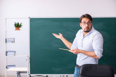 Tahtanın önündeki genç erkek öğretmen.