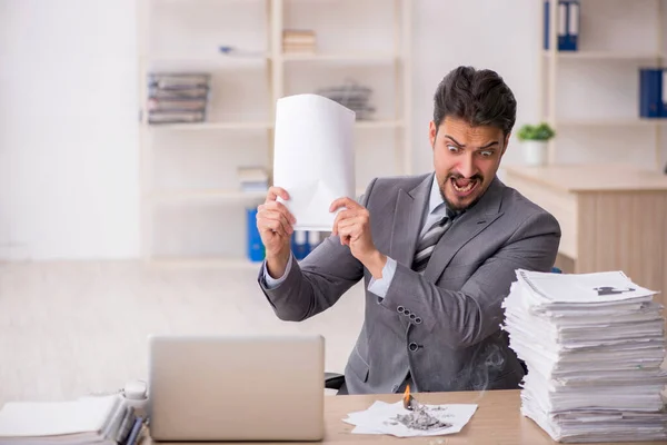 Jonge mannelijke werknemer ongelukkig met overmatig werk in het kantoor — Stockfoto