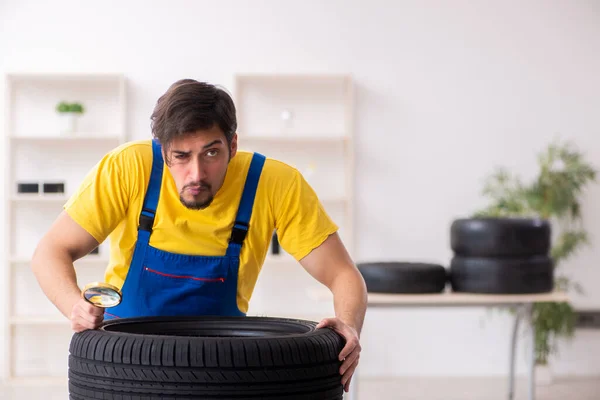 작업장에서 타이어를 사용하는 젊은 남자차고 노동자 — 스톡 사진