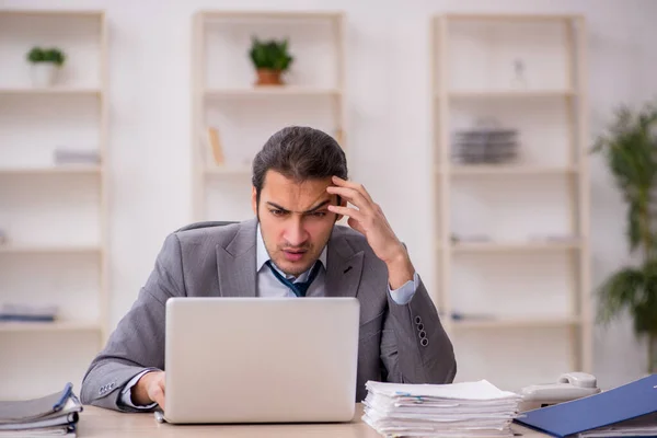 Joven empleado masculino descontento con el trabajo excesivo en la oficina — Foto de Stock