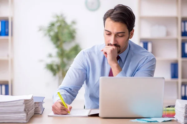 Joven empleado masculino y demasiado trabajo en la oficina — Foto de Stock