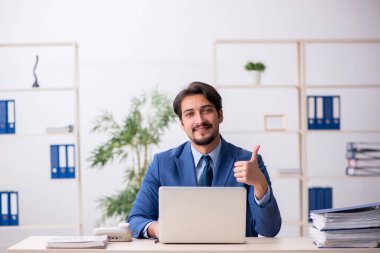 Genç bir erkek çalışan ve ofiste çok fazla iş var.