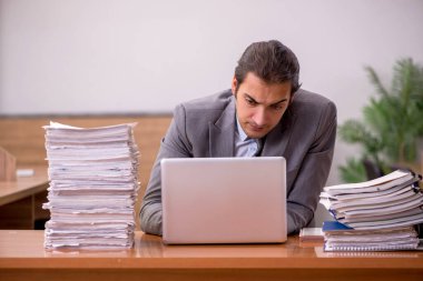 Genç bir erkek çalışan ve ofiste çok fazla iş var.