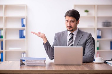 Genç çekici erkek çalışan işyerinde oturuyor.