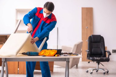 Genç erkek marangoz salgın sırasında ofiste çalışıyor.