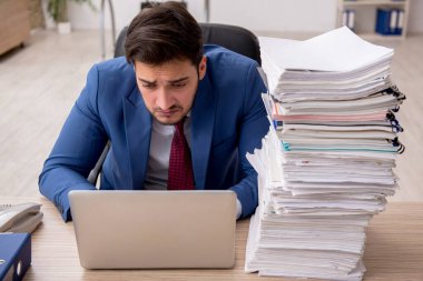 Genç bir erkek çalışan ve ofiste çok fazla iş var.