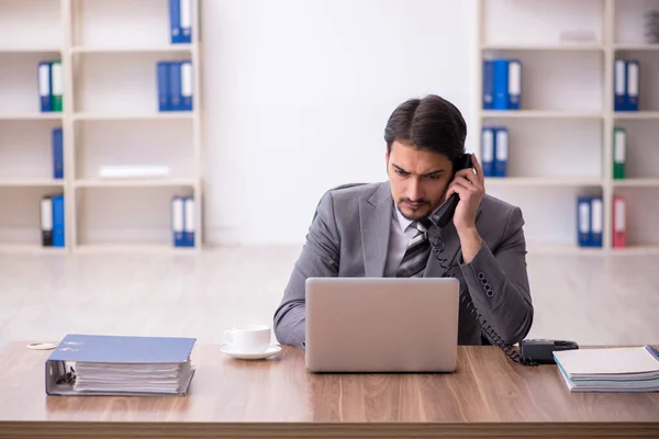 Jovem atraente masculino empregado sentado no local de trabalho — Fotografia de Stock