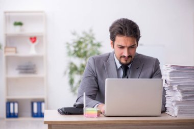 Genç bir erkek çalışan ve ofiste çok fazla iş var.