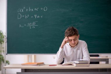 Okul çocuğu tahtanın önünde matematik çalışıyor.