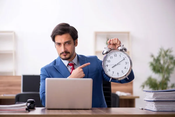 Jonge mannelijke werknemer in tijdmanagementconcept op de werkplek — Stockfoto