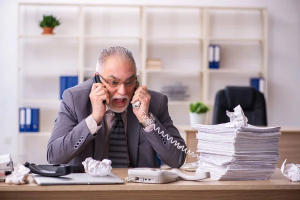 Oude mannelijke werknemer die op de werkplek werkt — Stockfoto