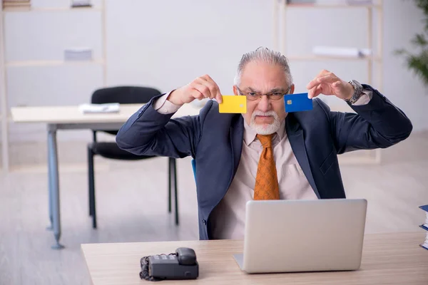 Alte männliche Angestellte mit Kreditkarte im Büro — Stockfoto