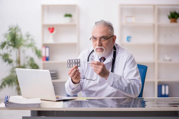 Klinikte çalışan yaşlı erkek doktor. — Stok fotoğraf