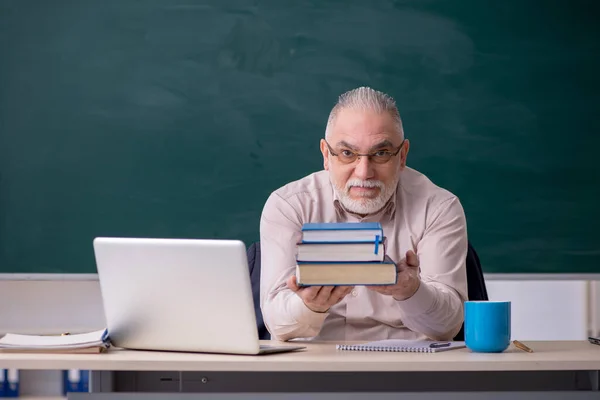 Old male teacher in front of blackboard — Stock Photo, Image