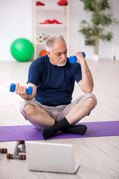 Oude man doet sport oefeningen binnen — Stockfoto