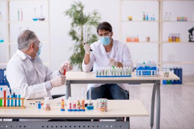 Laboratuvarda uyuşturucu sentezi konseptinde iki erkek kimyager.