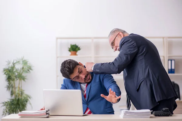 Old boss and young male employee in bullying concept — Stock Photo, Image