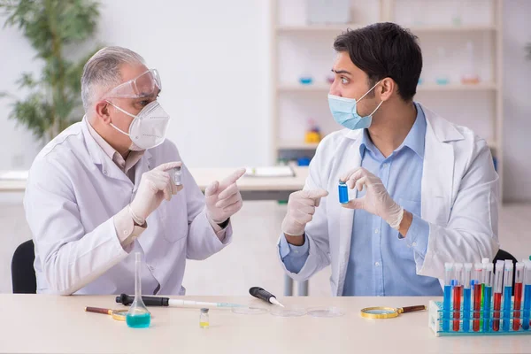 Два хіміки чоловічої статі працюють в лабораторії під час пандемії — стокове фото