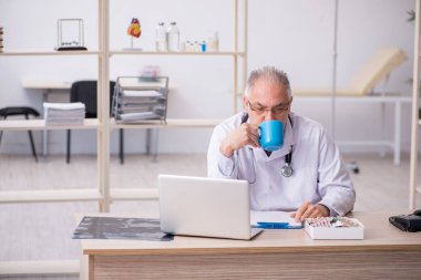 Klinikte çalışan yaşlı erkek doktor.