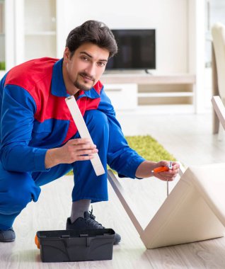 Müteahhit evde kırık sandalyeyi tamir ediyor.