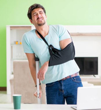 Koltuk değnekli yaralı bir adam evde oturuyor.