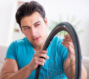 Evde bisiklet tamir eden genç bir adam.