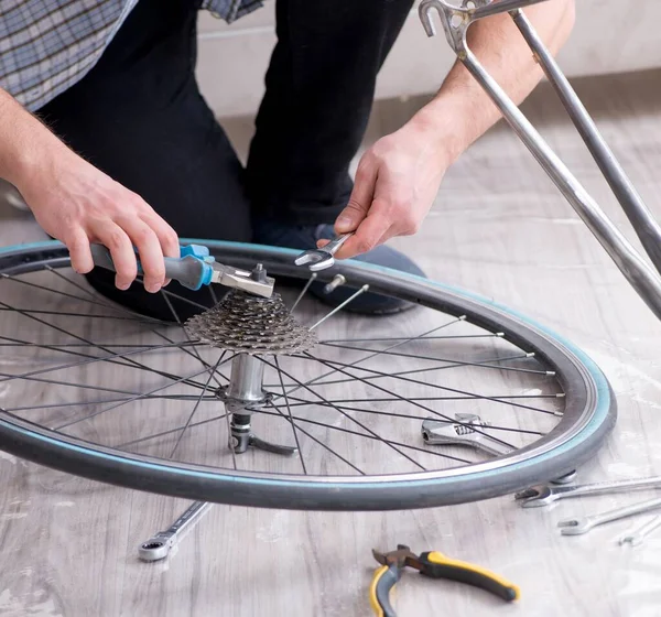 Giovane uomo che ripara la bicicletta a casa — Foto Stock