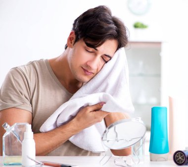 Genç yakışıklı adam aynaya bakıyor.