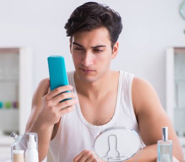 Genç yakışıklı adam aynaya bakıyor.