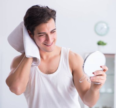 Genç yakışıklı adam aynaya bakıyor.