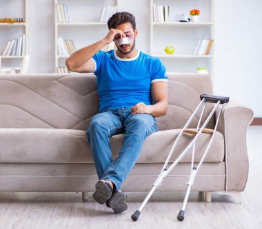 Koltuk değnekli yaralı bir adam evde iyileşiyor.