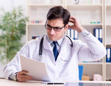 Genç doktor ofiste oturuyor.