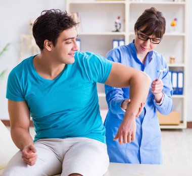 Doktor çekiçle sinir reflekslerini kontrol ediyor