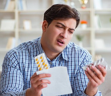 Kanepede ilaç ve reçeteyle oturan genç adam.