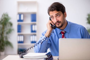 Ofisteki aşırı işten memnun olmayan genç bir erkek işçi.